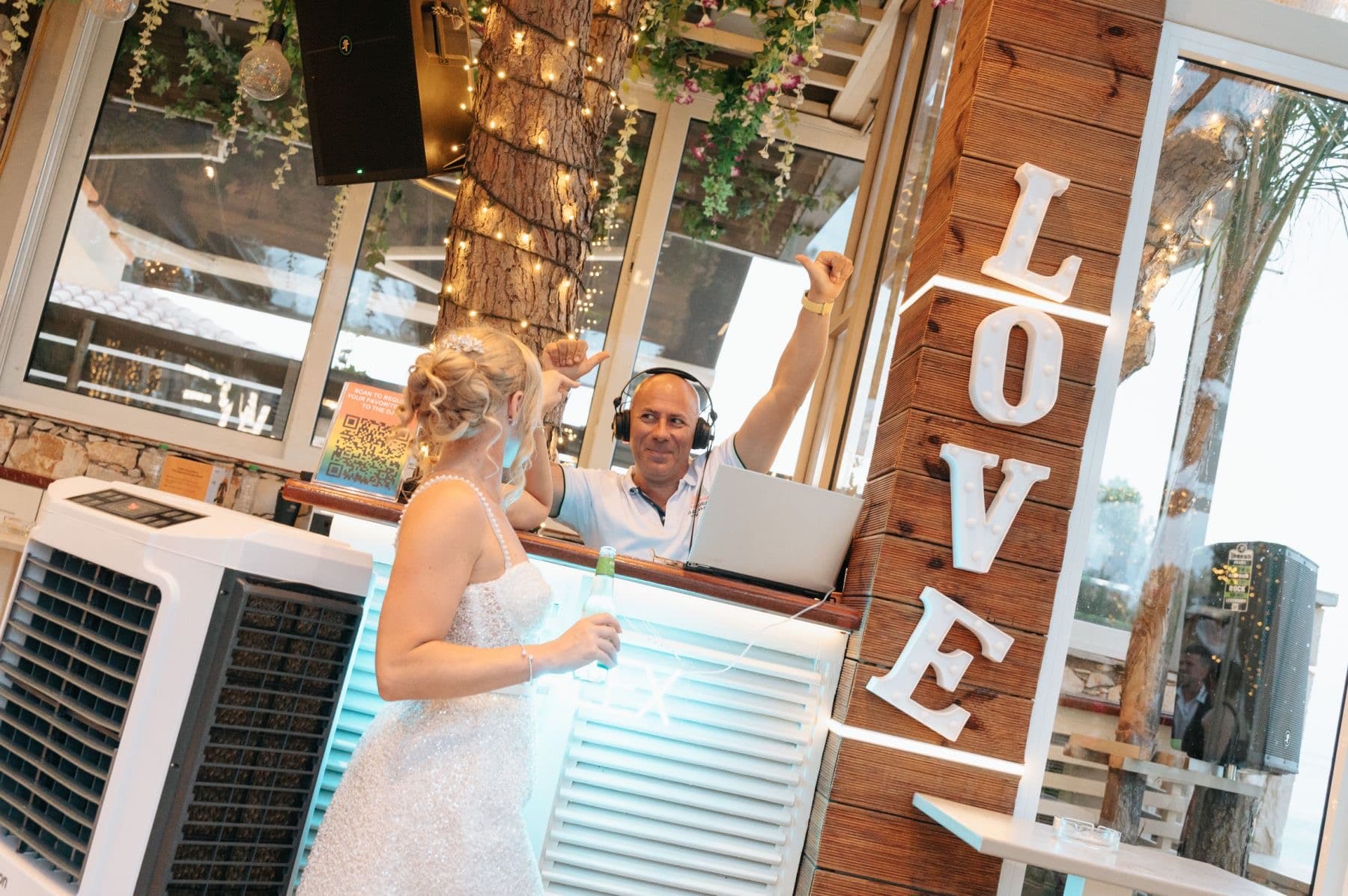 Bride at the DJ booth with LOVE sign at a Zante wedding